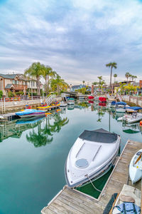 Boats moored at harbor against sky