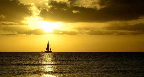 Silhouette sailboat sailing on sea against sky during sunset