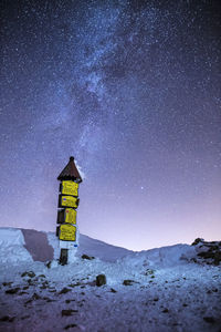 Information sign on field against sky at night