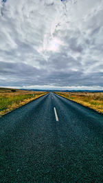 Road amidst field against sky