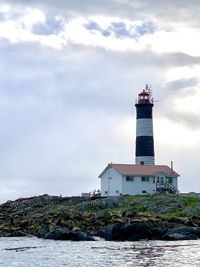 Lighthouse by sea against sky with seals