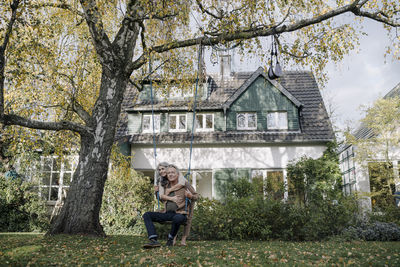 Happy woman embracing senior man on a swing in garden