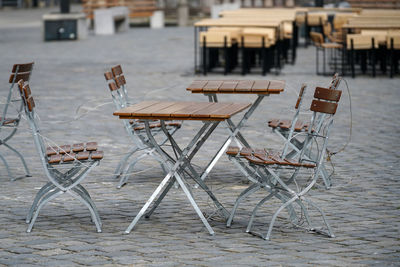 Empty chairs and tables at sidewalk cafe in city