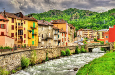 Houses by river amidst buildings against sky