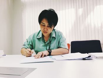 Mid adult man using mobile phone while sitting on table