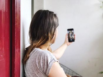 Young woman taking selfie through mobile phone at home