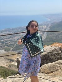 Side view of girl standing on mountain against sky during sunny day