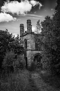 Old building by trees against sky