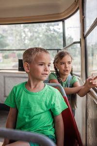 Kids ride in empty tram and look at the window with interest, public transportation, city tramway