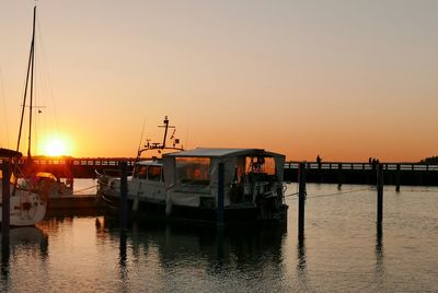 Boats moored at harbor against clear sky during sunset