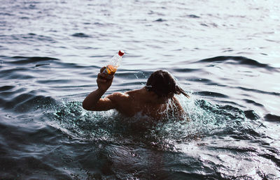 Rear view of shirtless man swimming in sea