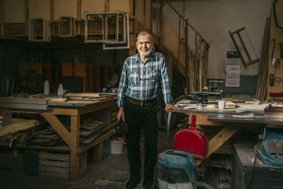 Senior craftsman standing near workbench at carpentry workshop