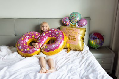 Portrait of girl with balloon lying on bed at home