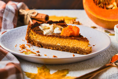 Homemade pumpkin cheesecake decorated with whipped cream on gray plate.