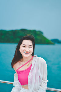 Portrait of young woman standing against sea