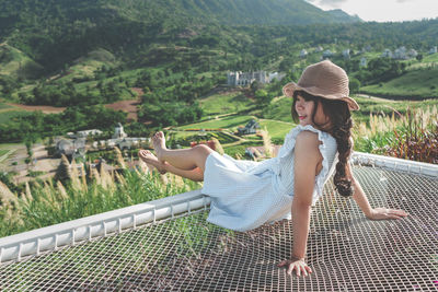 Woman wearing hat on mountain against trees