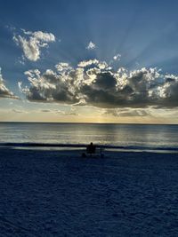 Silhouette people on beach against sky during sunset