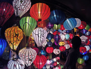 Side view of man arranging illuminated lanterns at market stall
