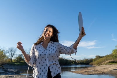 Young woman standing by water against sky