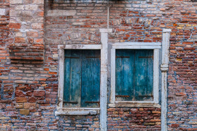 Closed windows on abandoned brick wall