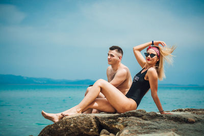 Young couple on sea shore against sky