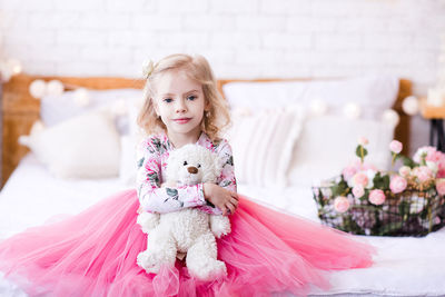 Cute girl in pink dress sitting with teddy bear