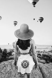 Rear view of woman standing at beach against sky