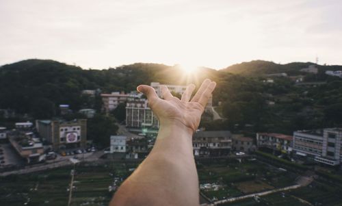 Midsection of man with cityscape against sky during sunset