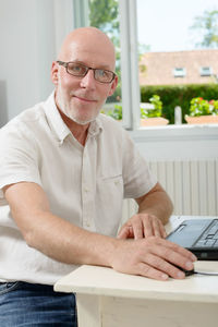 Portrait of man sitting with laptop at table