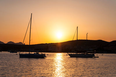 Silhouette sailboats in sea against sky during sunset