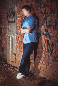 Full length of man standing against brick wall