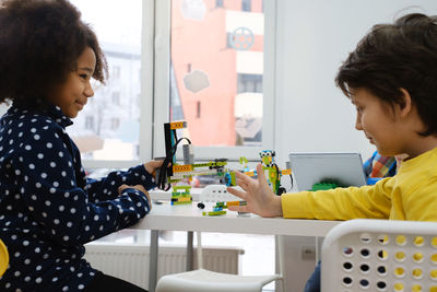 Coding class, school girl constructing robot arm mechanism. multiethnic children making science