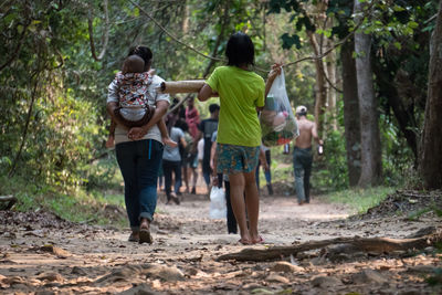 Rear view of people walking in forest