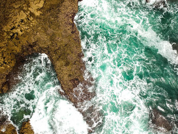 High angle view of sea waves splashing on rocks