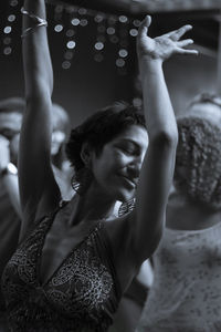 Midsection of woman with arms raised at music concert