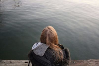 Rear view of woman sitting against lake