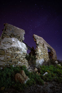 Low angle view of abandoned building against star field sky at night