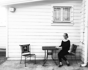 Woman sitting on chair outside building