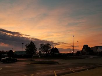 Cars on road against sky during sunset