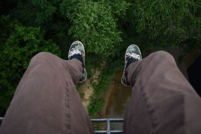 Low section of person dangling over trees by stream