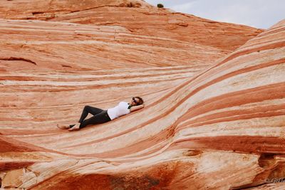 Woman lying on rock formation at valley of fire state park