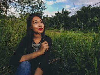 Beautiful young woman in grass against sky