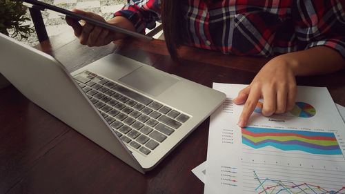 Midsection of businesswoman analyzing data on desk in office