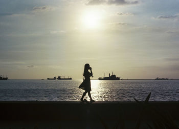 Silhouette woman walking on promenade against sky