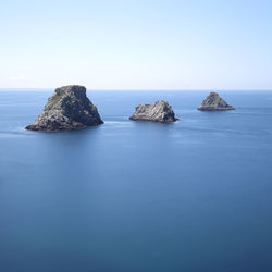 Rocks in sea against clear sky