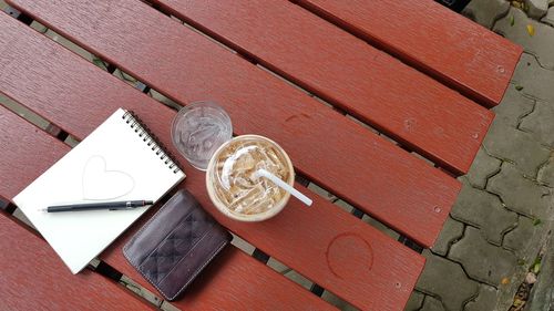 Top view of ice coffee, ice water, wallet and notebook on table