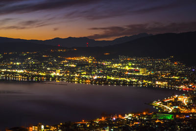 High angle view of illuminated cityscape against sky at night