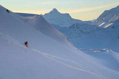 People skiing on snowcapped mountains against sky