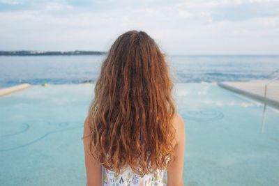 Rear view of man standing by sea against sky