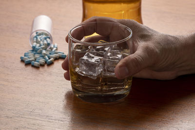 Alcohol abuse with glass of whiskey with ice and pills